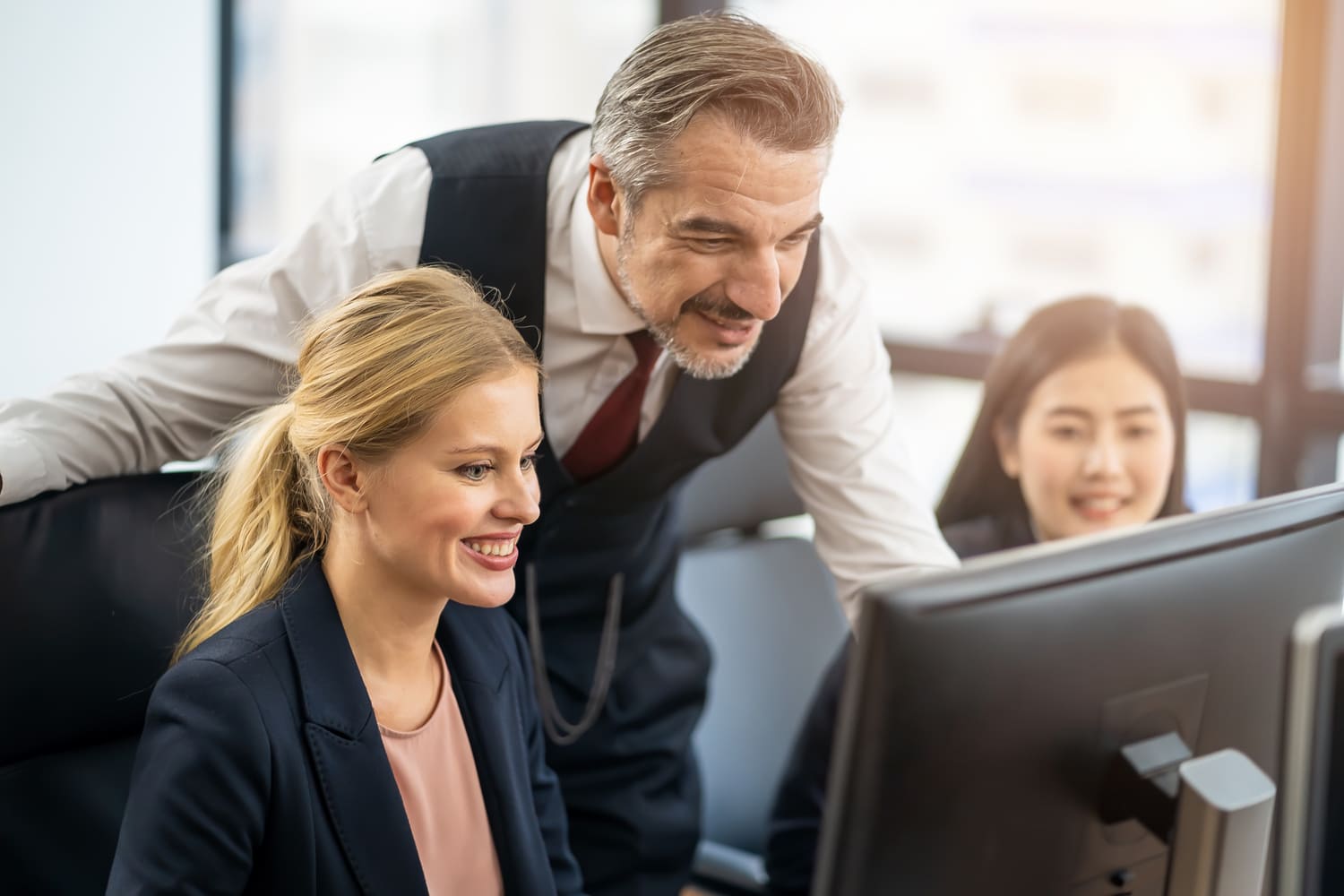 Un equipo de trabajo sonriendo y mirando hacia una pantalla de computadora en la oficina.